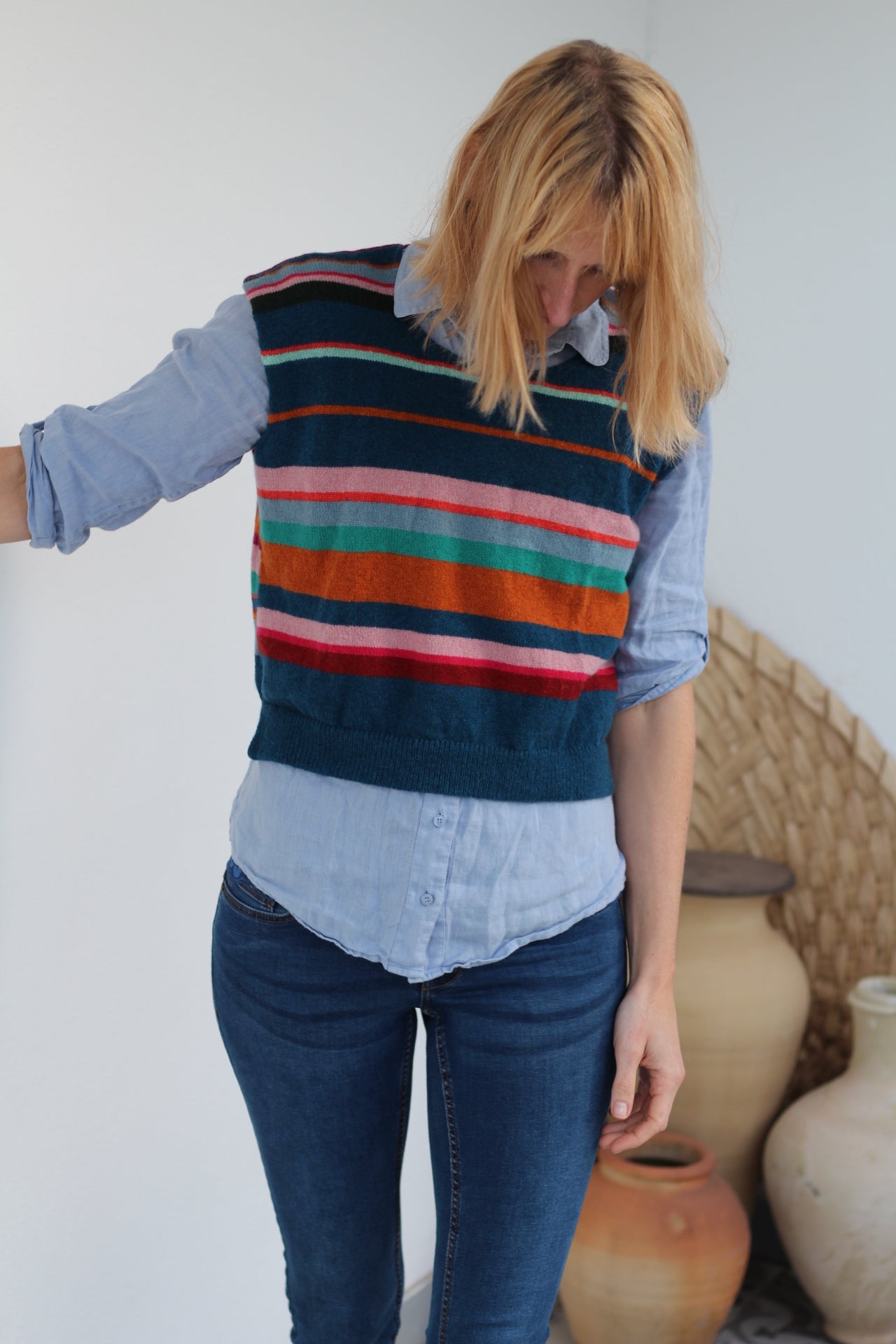 Person wearing a colorful striped sweater and blue jeans on a white background