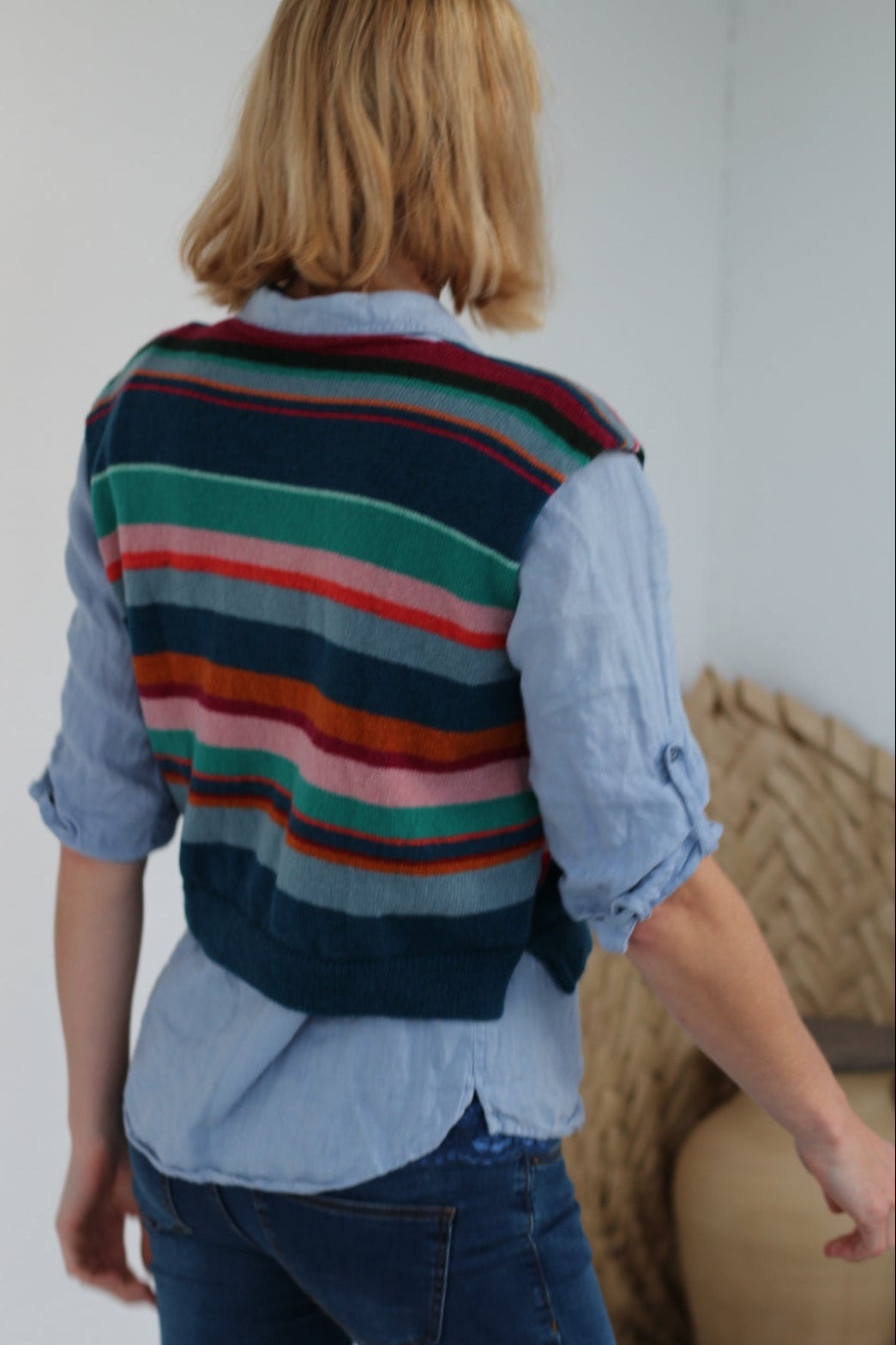 Person wearing a striped sweater and blue jeans on a white surface.