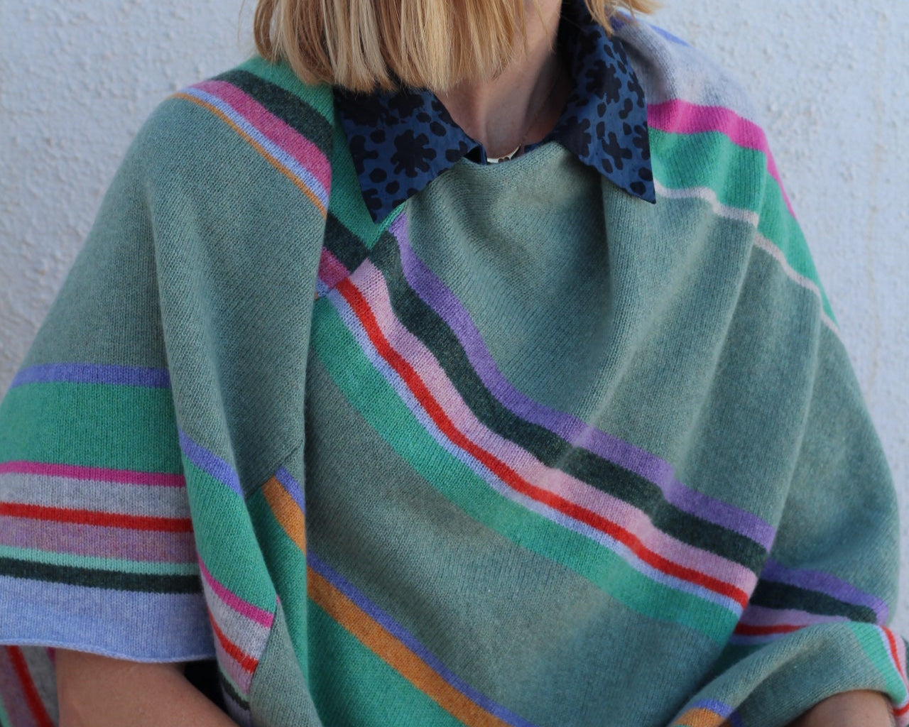 Person wrapped in a colorful blanket with a white background