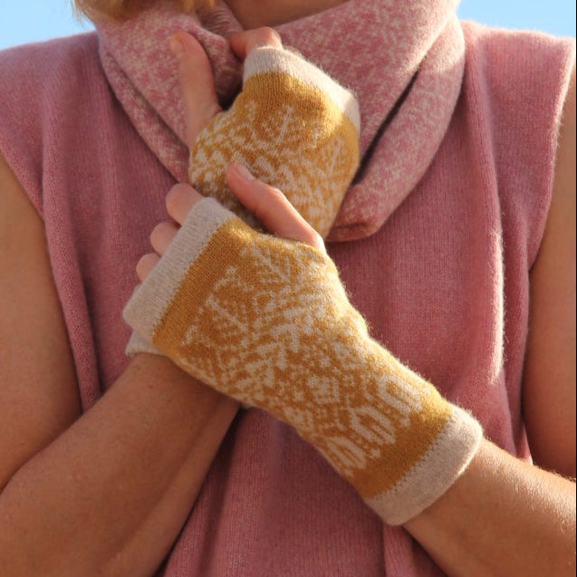 Woman wearing a pink sweater and yellow gloves against a blue sky.