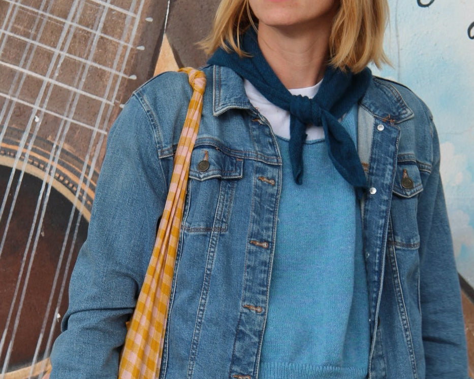Person wearing a blue denim jacket lying on a guitar with a scenic background