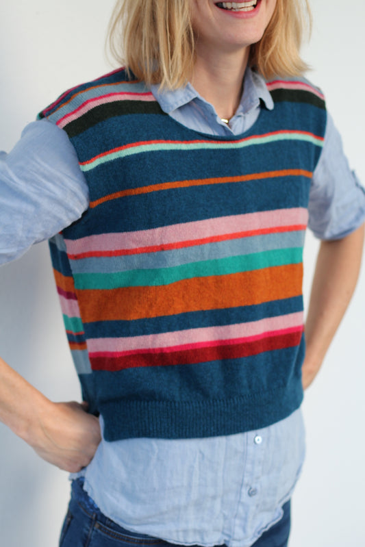 Person wearing a colorful striped sweater on a plain background