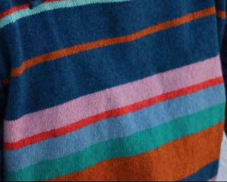 Woman holding a colorful striped fabric against a white wall