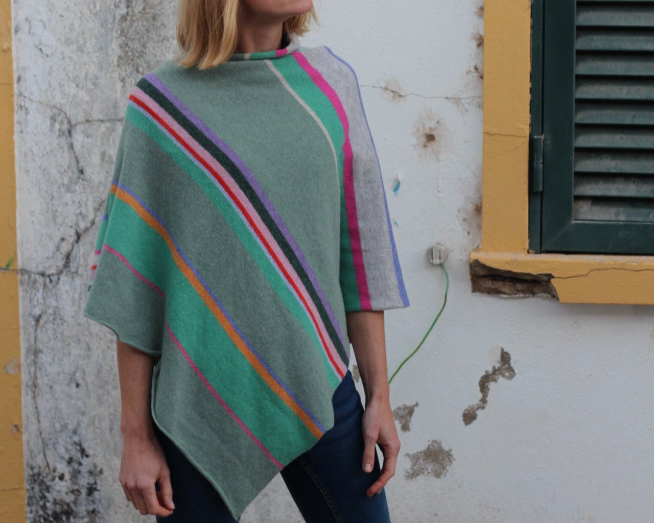 Person wearing a colorful striped poncho in an urban setting