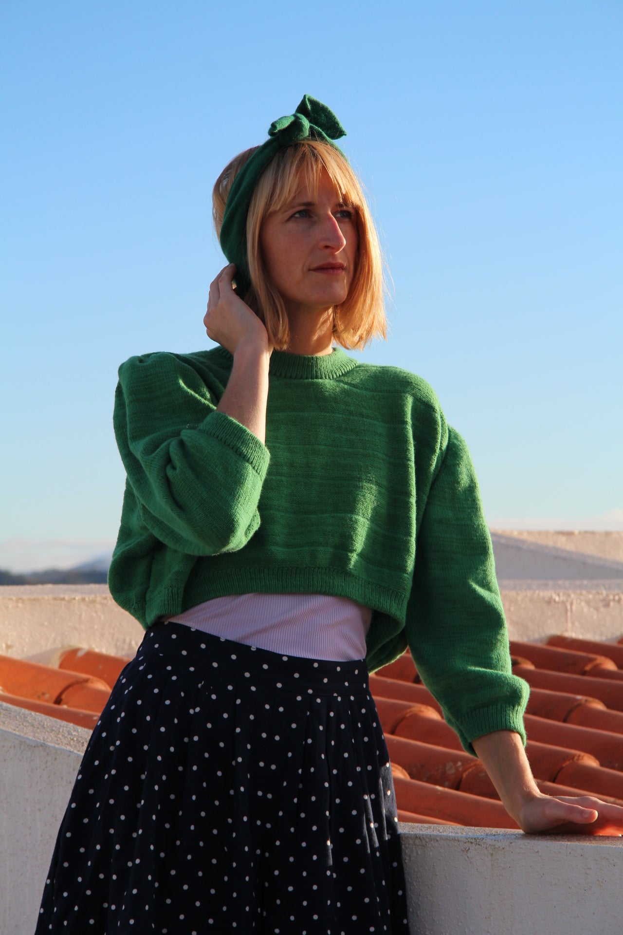 Person wearing a green outfit with a matching hat against a clear blue sky.