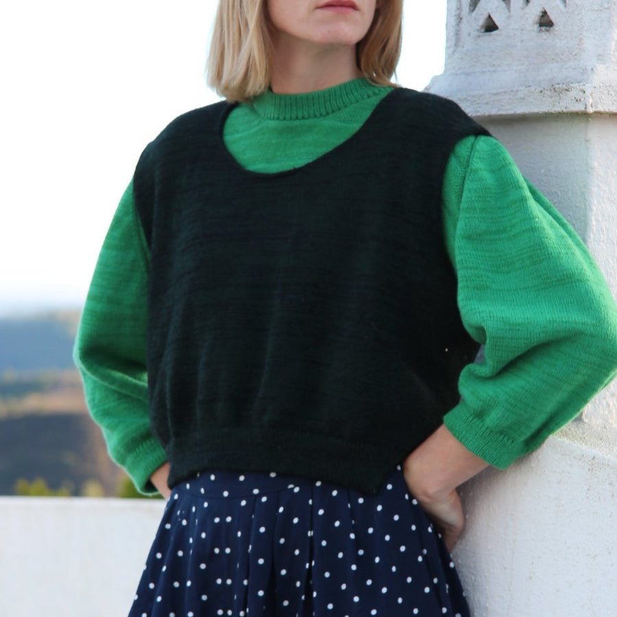 Woman wearing a green and black dress with a polka dot skirt, lying on a white surface.