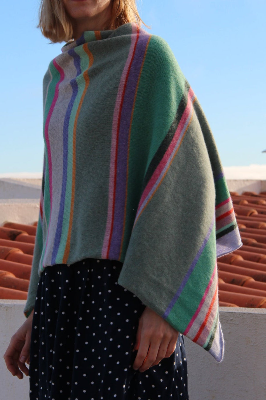 Person wearing a colorful striped poncho with a clear blue sky in the background