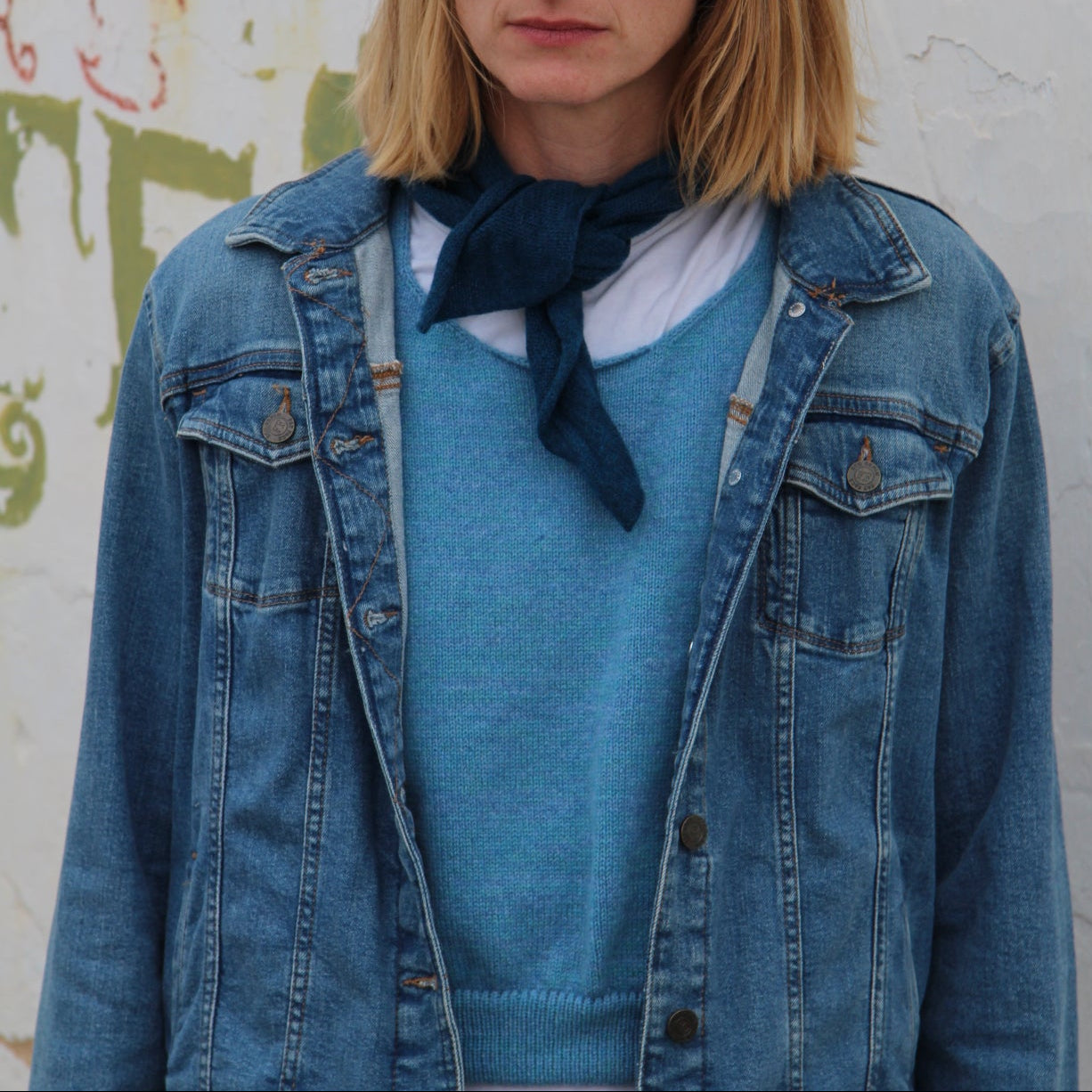Person wearing a blue denim jacket with a colorful abstract design in the background