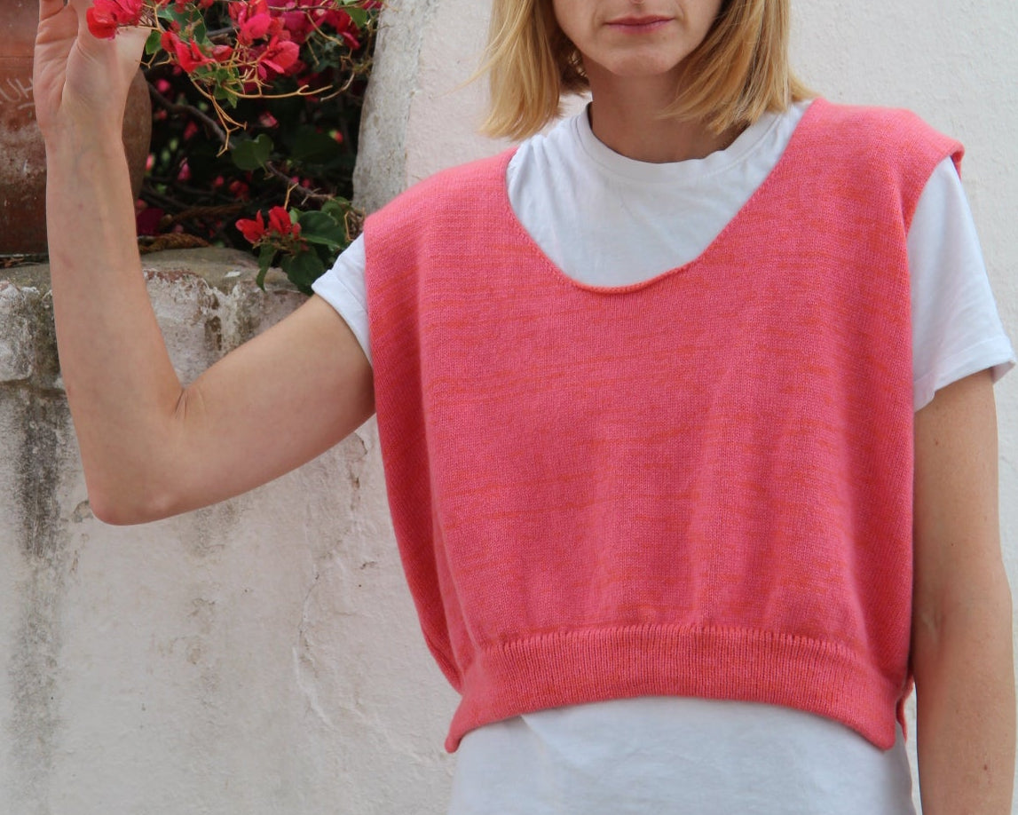 Woman in a pink and black outfit standing outdoors with flowers in the background