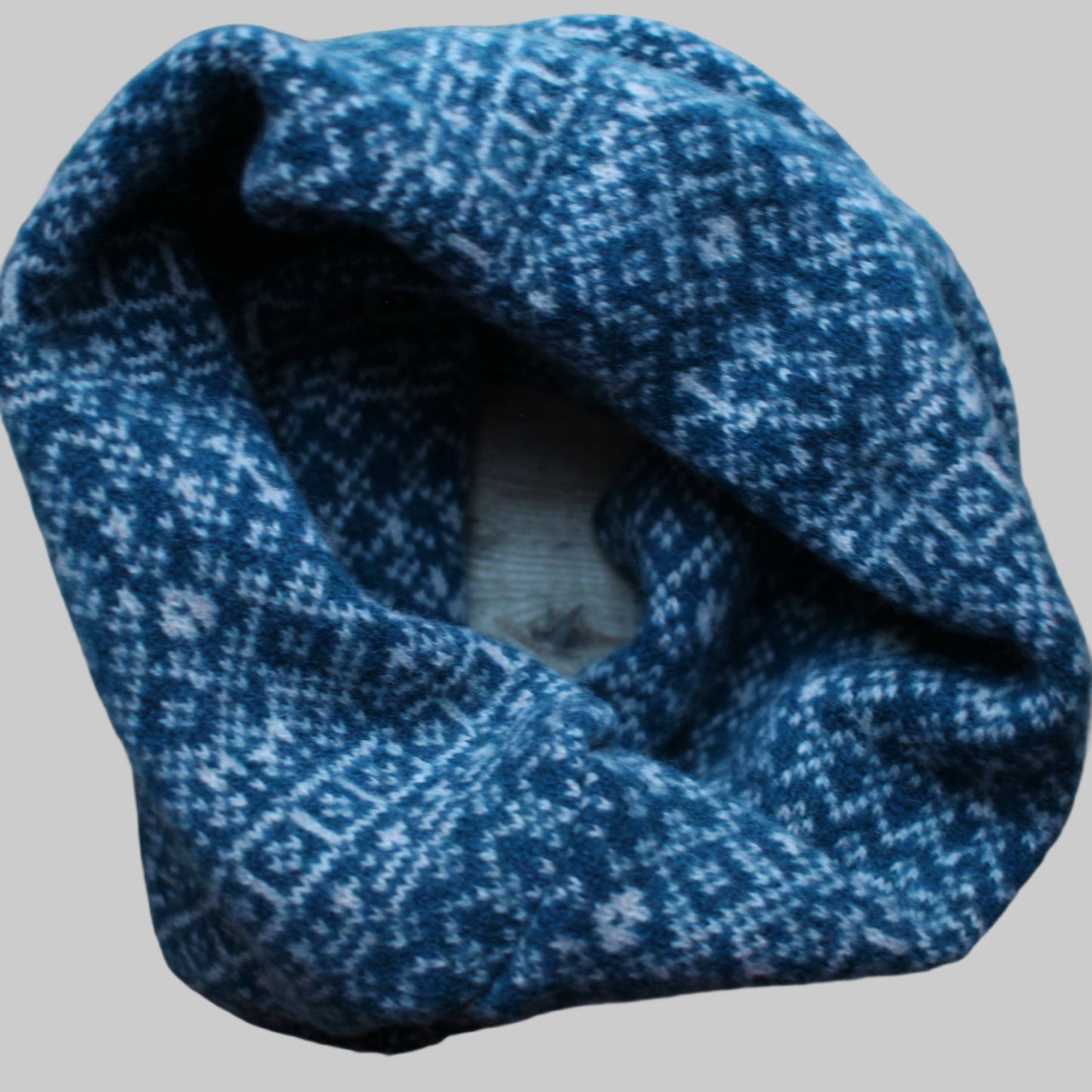 Blue knitted headband with a pattern on a wooden surface